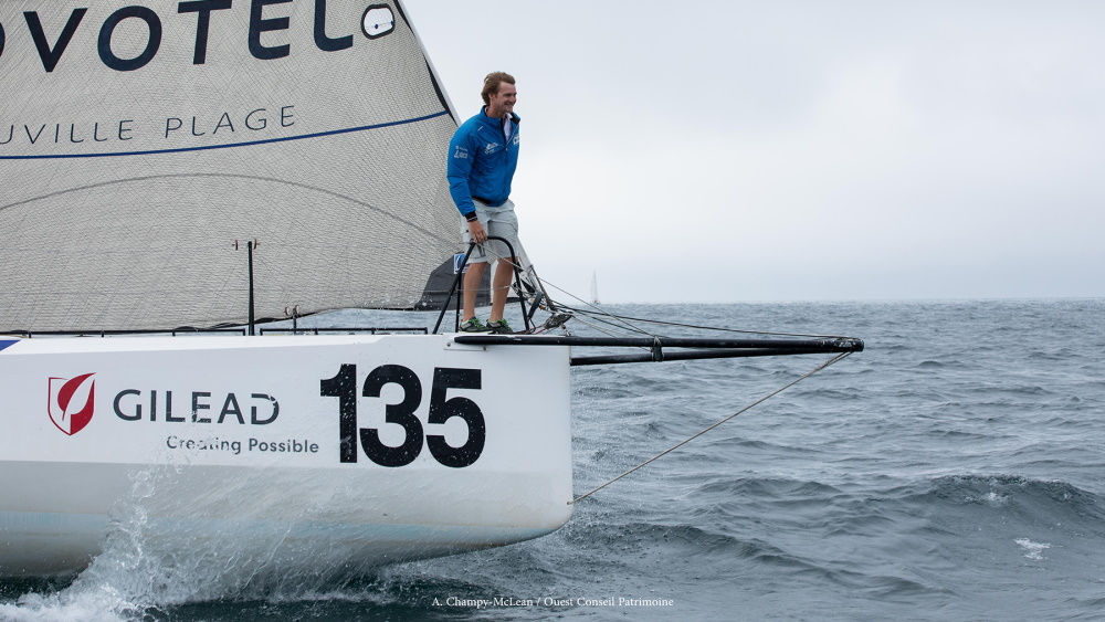 En man står på kanten av en yacht i rörelse