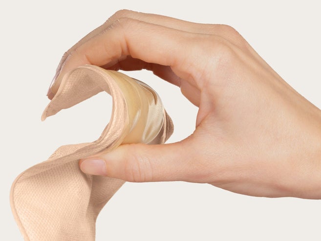 Handen trycker på plattan på en mjuk konvex stomipåse för att visa dess flexibilitet