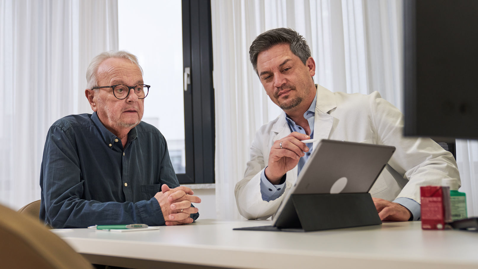 Onkolog konsulterar cancerpatient och ger råd via iPad 