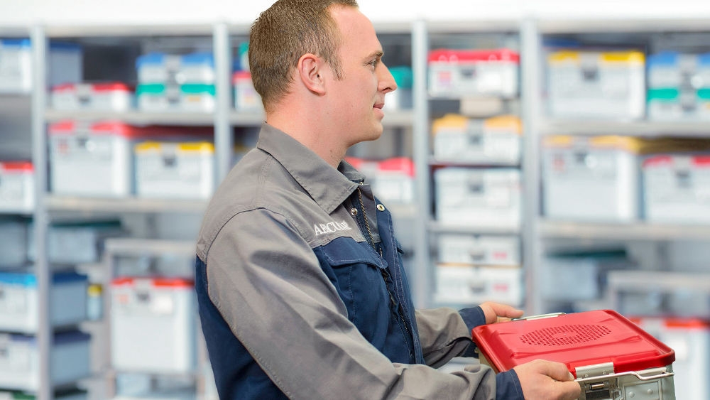 En servicetekniker från B. Braun överlämnar en låda med reservdelar för medicintekniska produkter.