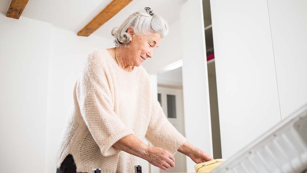 En äldre kvinna packar sin resväska och ler