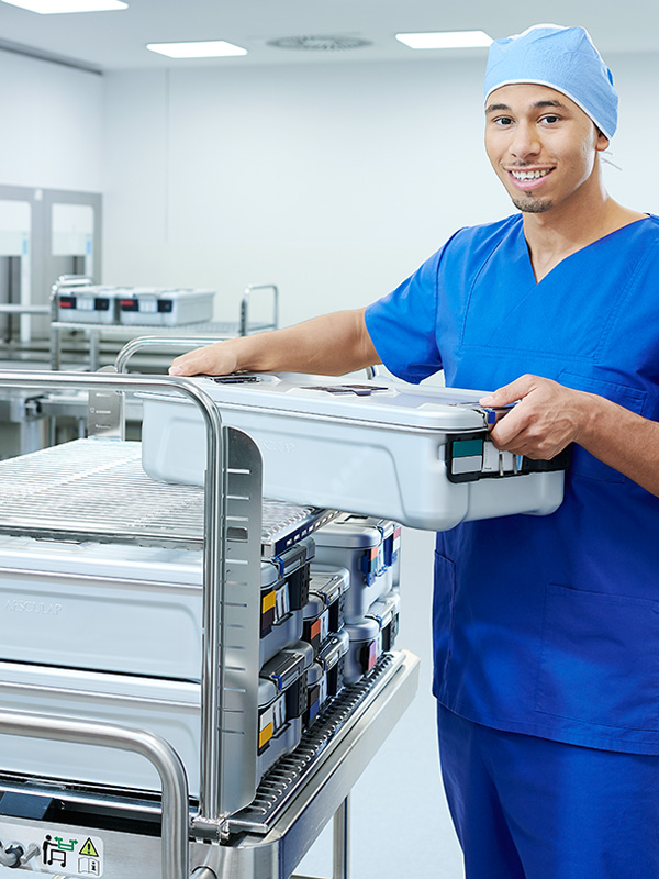 En manlig sjukvårdspersonal håller en sterilcontainer med ett leende