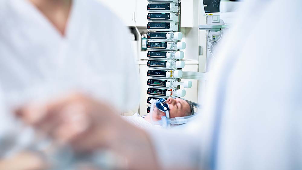 Patienten ligger på en intensivvårdsavdelning och har många B. Braun infusionspumpar i bakgrunden