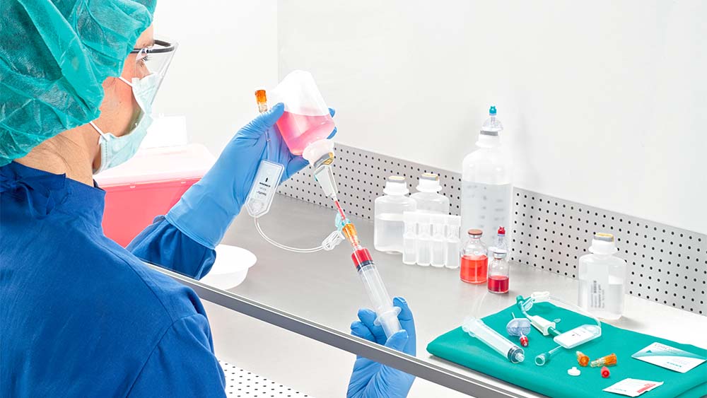 Apotekaren drar upp spruta under lamina airflow