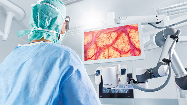 En kirurg utför neurokirurgi med Aesculap Aeos® medan han står upprätt och tittar på bildskärmen. 