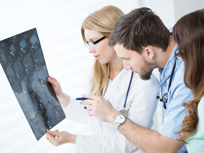 Tre sjukvårdspersonal analyserar en fluorografibild och pekar ut specifika intresseområden